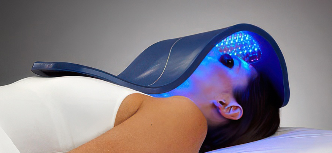 Client receiving LED light therapy under a Celluma device to treat acne and improve skin health in Orange, CA.